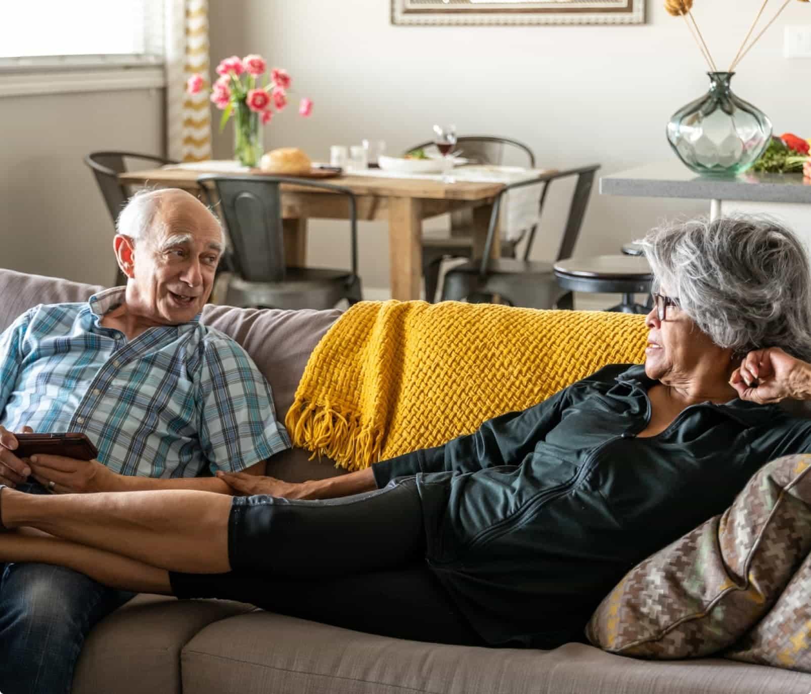 A grey-haired man and woman relaxing on a couch.