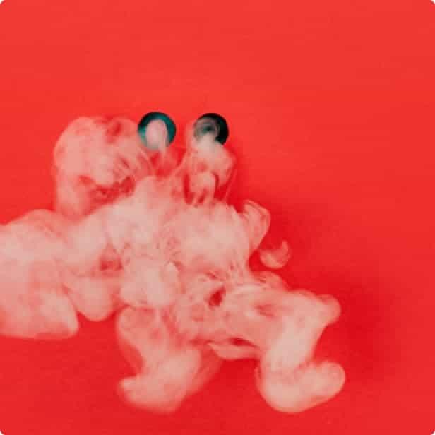 Two puffs of smoke emerging from a red wall.